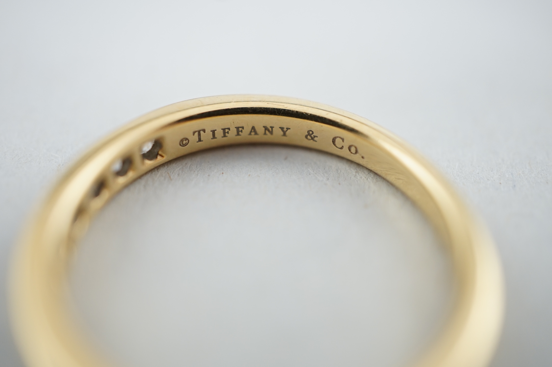 A modern Tiffany & Co 18k gold and channel set thirteen stone diamond half eternity ring